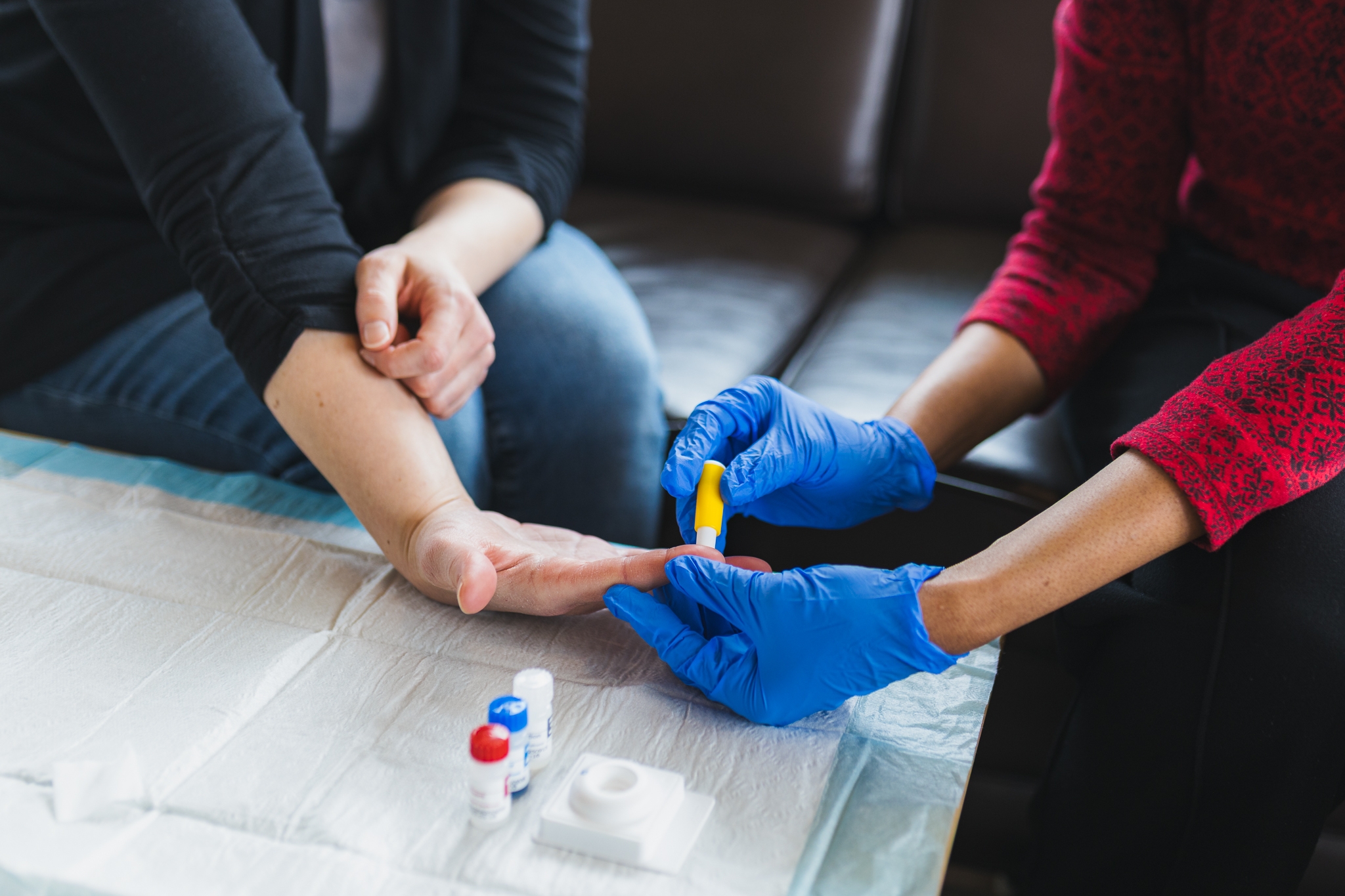 Close-up photo of hands, giving a finger prick test that checks for syphilis.